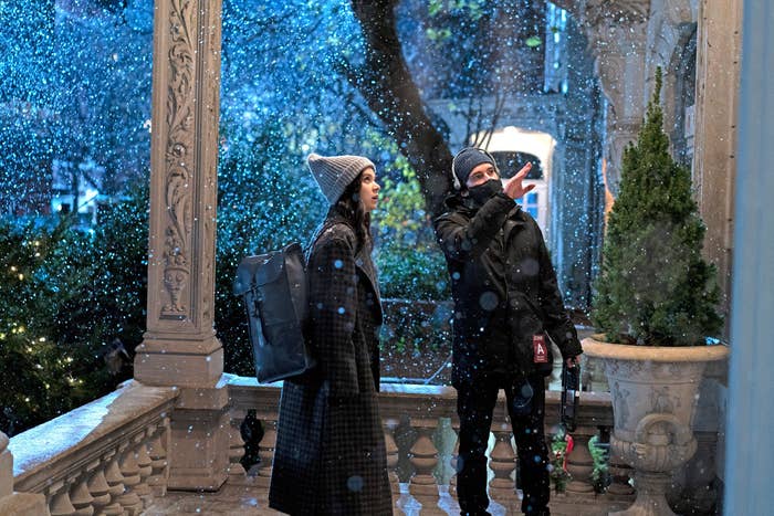 Hailee standing on a snowy porch as she discusses something with Rhys