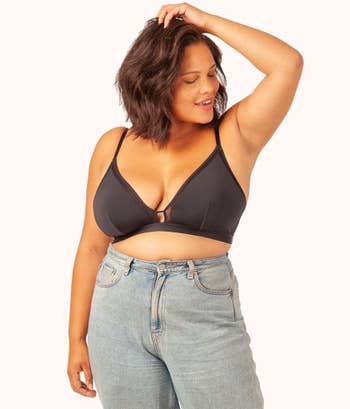 Front of model wearing black triangle bralette with blue jeans