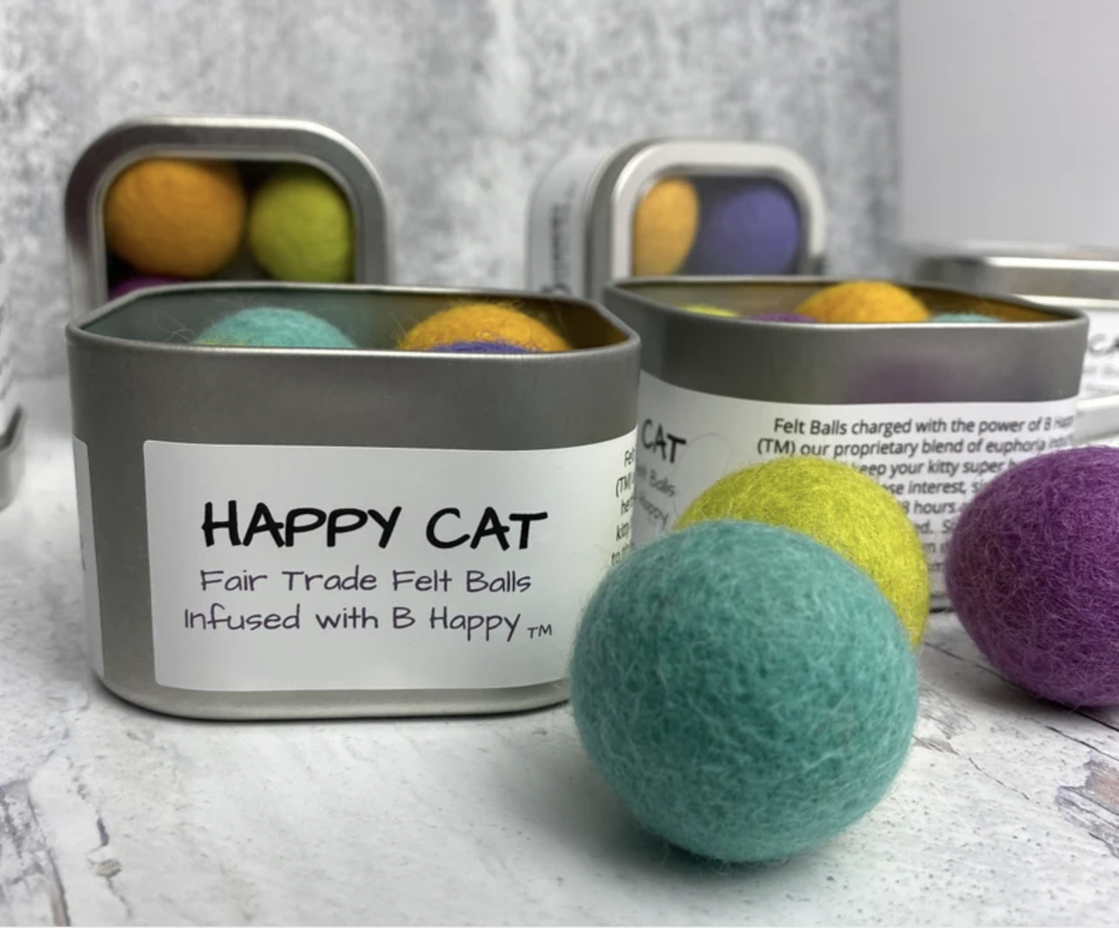 Four tins that say &quot;Happy Cat&quot; filled with multi-colored felt balls