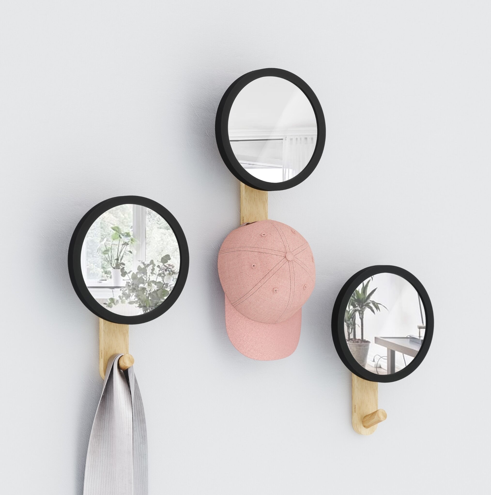 a trio of circular mirrors with hooks hung on a wall