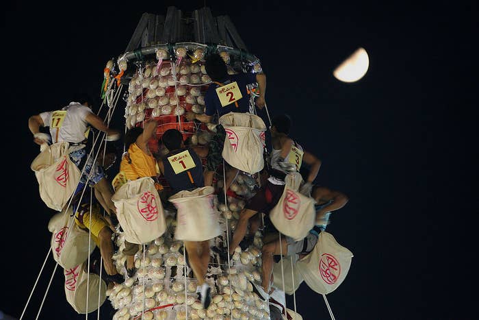 Young men holding sacks and climbing up bun towers for a celebration of the traditional Cheung Chau Bun Festival of Hong Kong