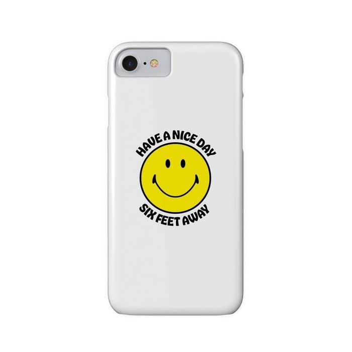 White phone case with a yellow smiley face with the words "have a nice day six feet away"