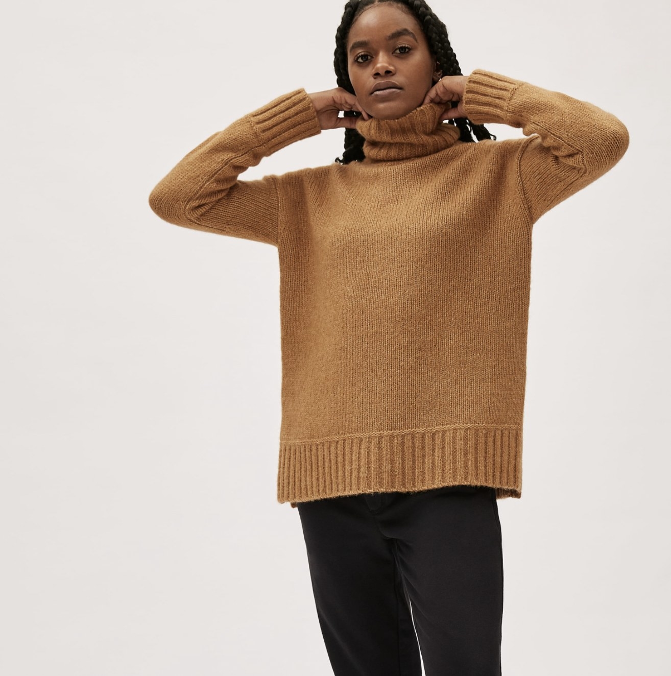 A model wearing the high cut beige turtleneck with leggings