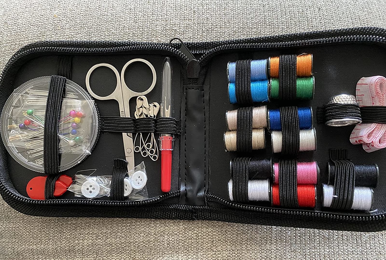 the sewing kit with different strings and other scissors and pins in the kit