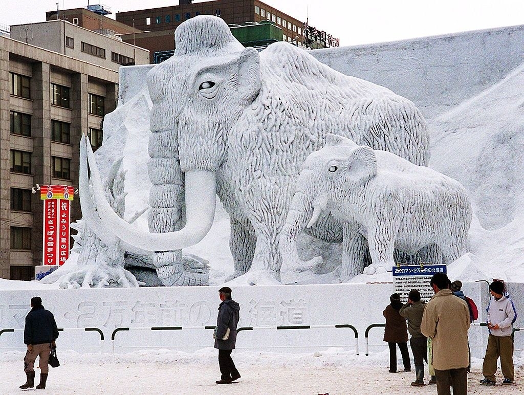 People admire snow sculptures of mammoths at the Sapporo Snow Festival