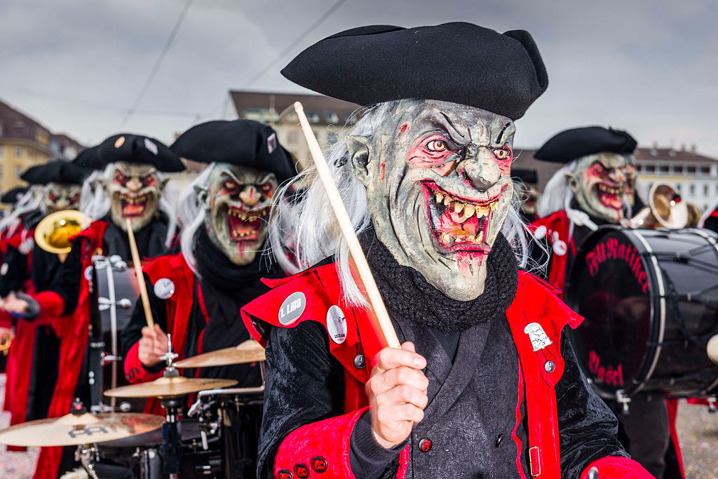 A parade of people masked as creatures, with drums in their hands, celebrating the Carnival of Basel