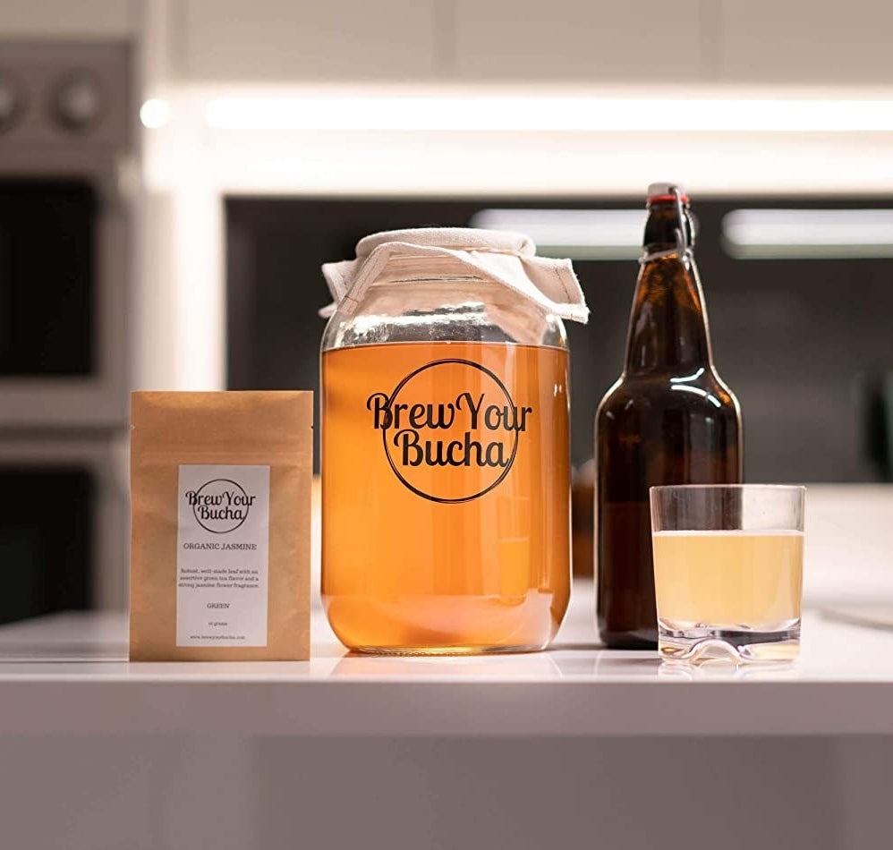The components of the kit displayed on a counter top with a glass of kombucha