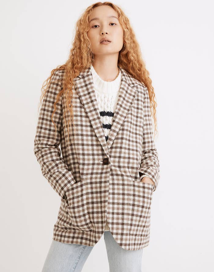 A model wearing an oversized blazer with a checkered neutral-colored pattern and a button at the middle