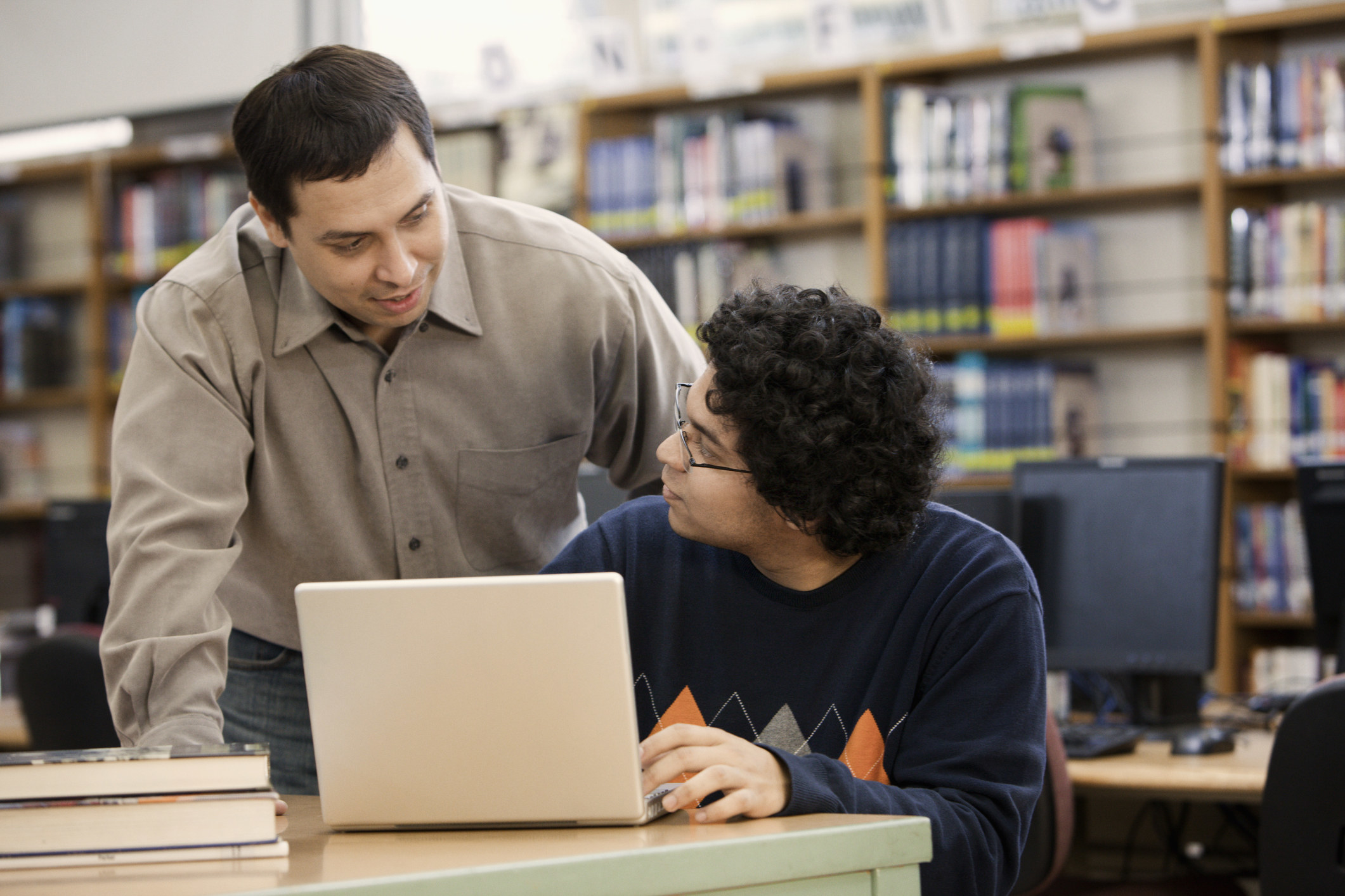 A librarian helps a student working on a laptop