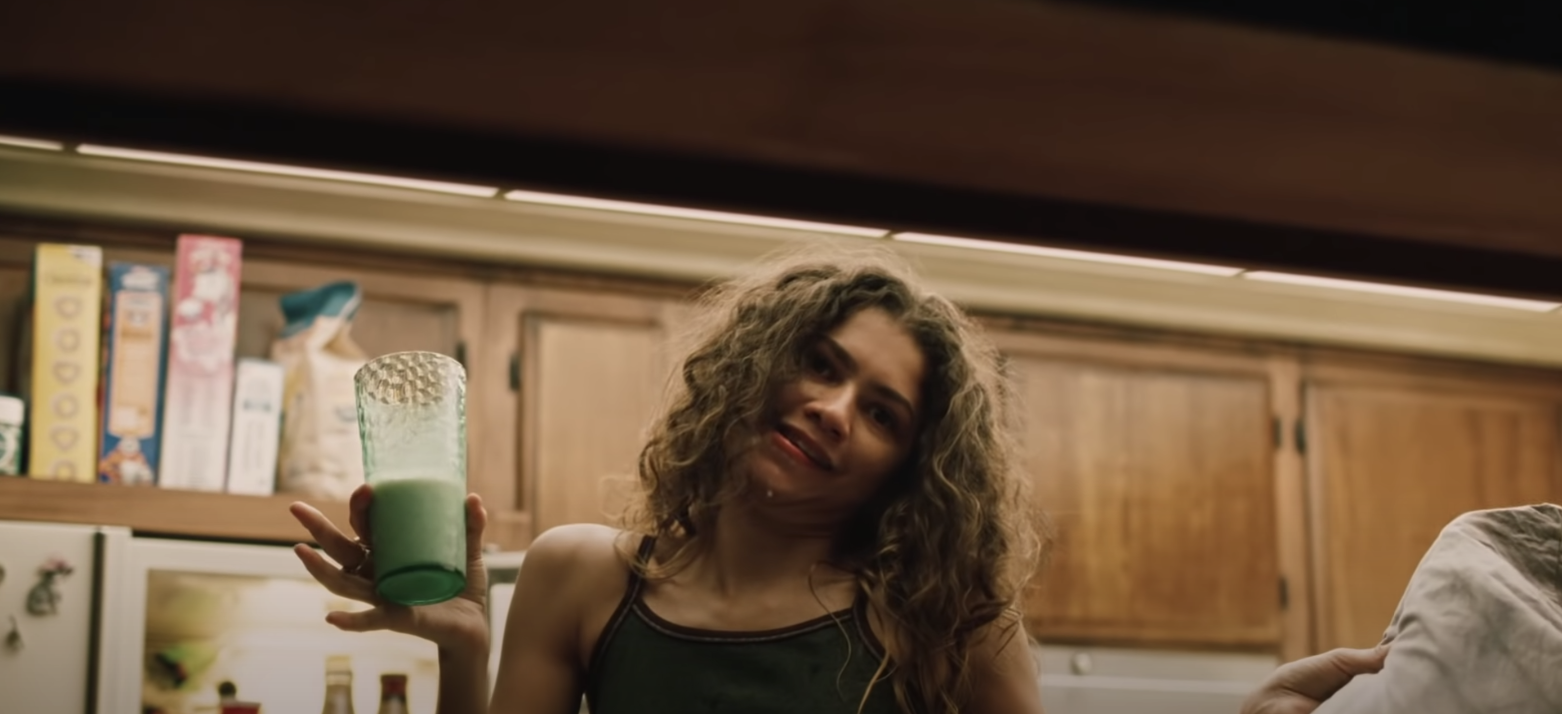 Rue in the kitchen holding a glass of what looks like milk