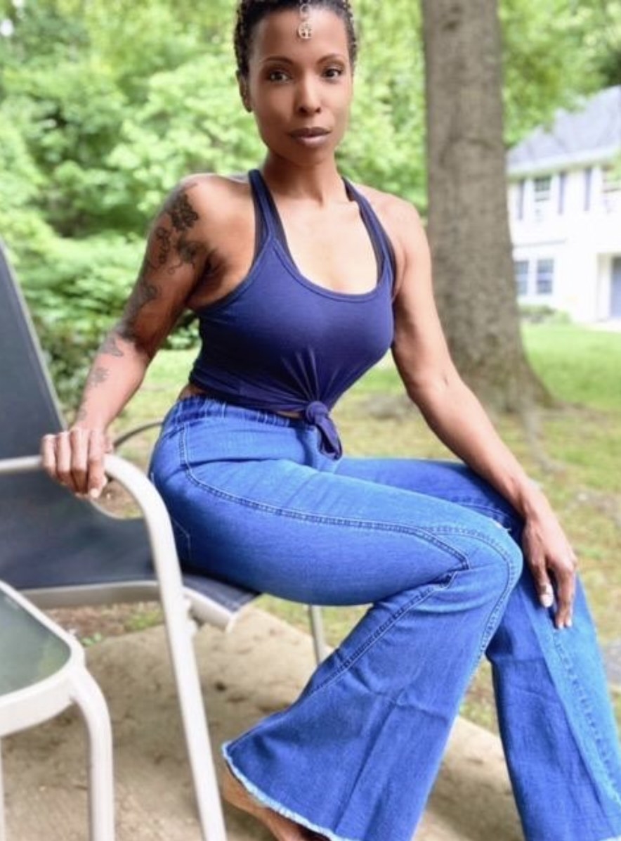 Reviewer lounging in a patio chair wearing the flare jeans in a medium blue wash