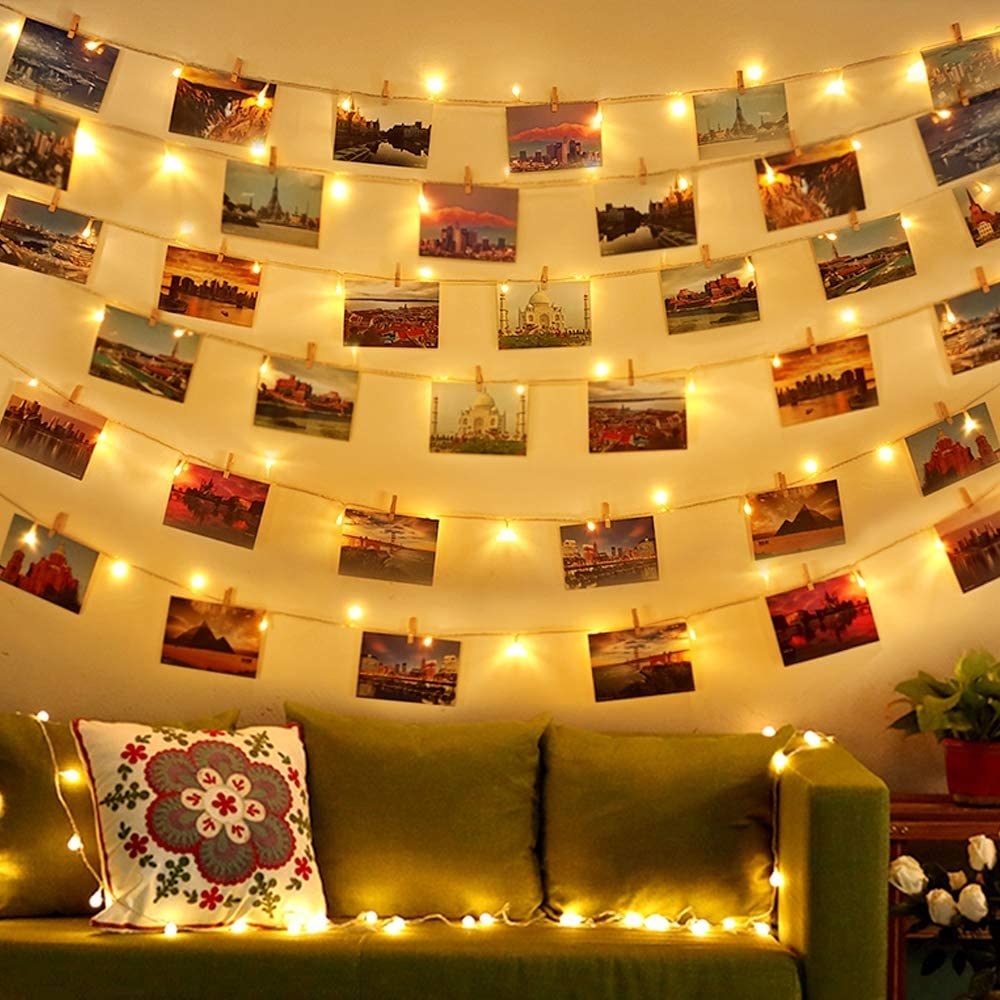 Six rows of glowing fairy lights with pictures hanging from them on a wall