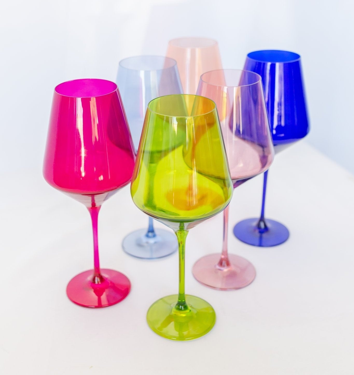 six wine glasses in different colors including hot pink, lime green, light pink, lavender, blue, and light blue