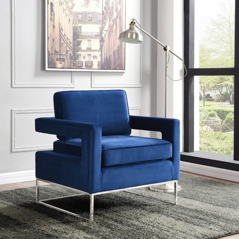 Navy blue armchair next to a floor lamp and area rug