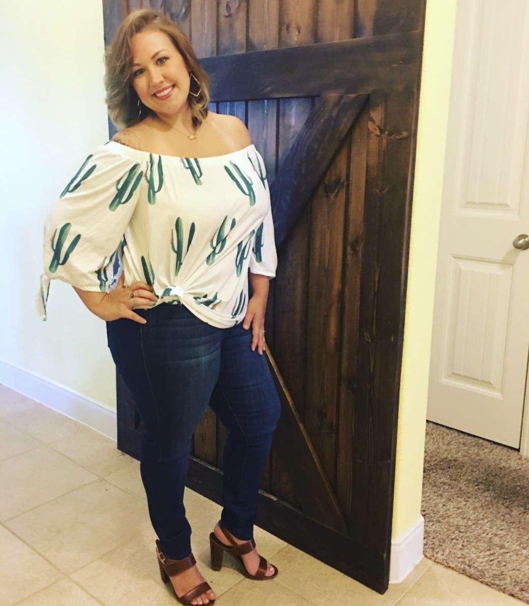 Reviewer wearing the dark blue jeans with a flowy off-the-shoulder cactus print top