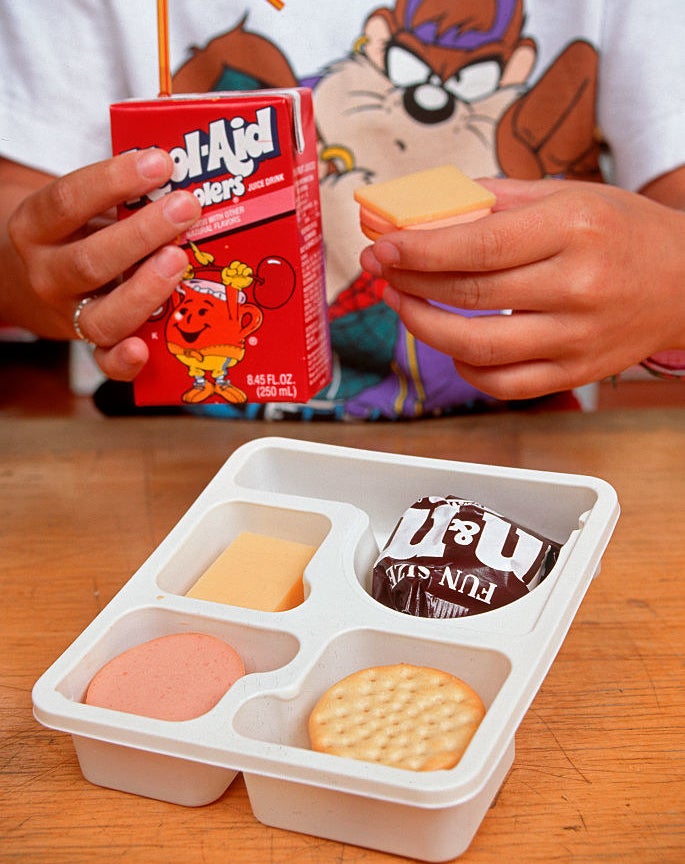 Photo of a kid drinking a Kool-Aid while eating a Lunchable
