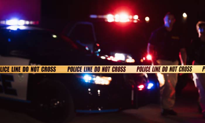 Police cars with lights on at night behind crime scene tape