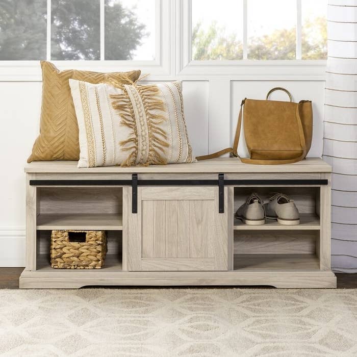 Bench shown with pillows, a bag and shoes