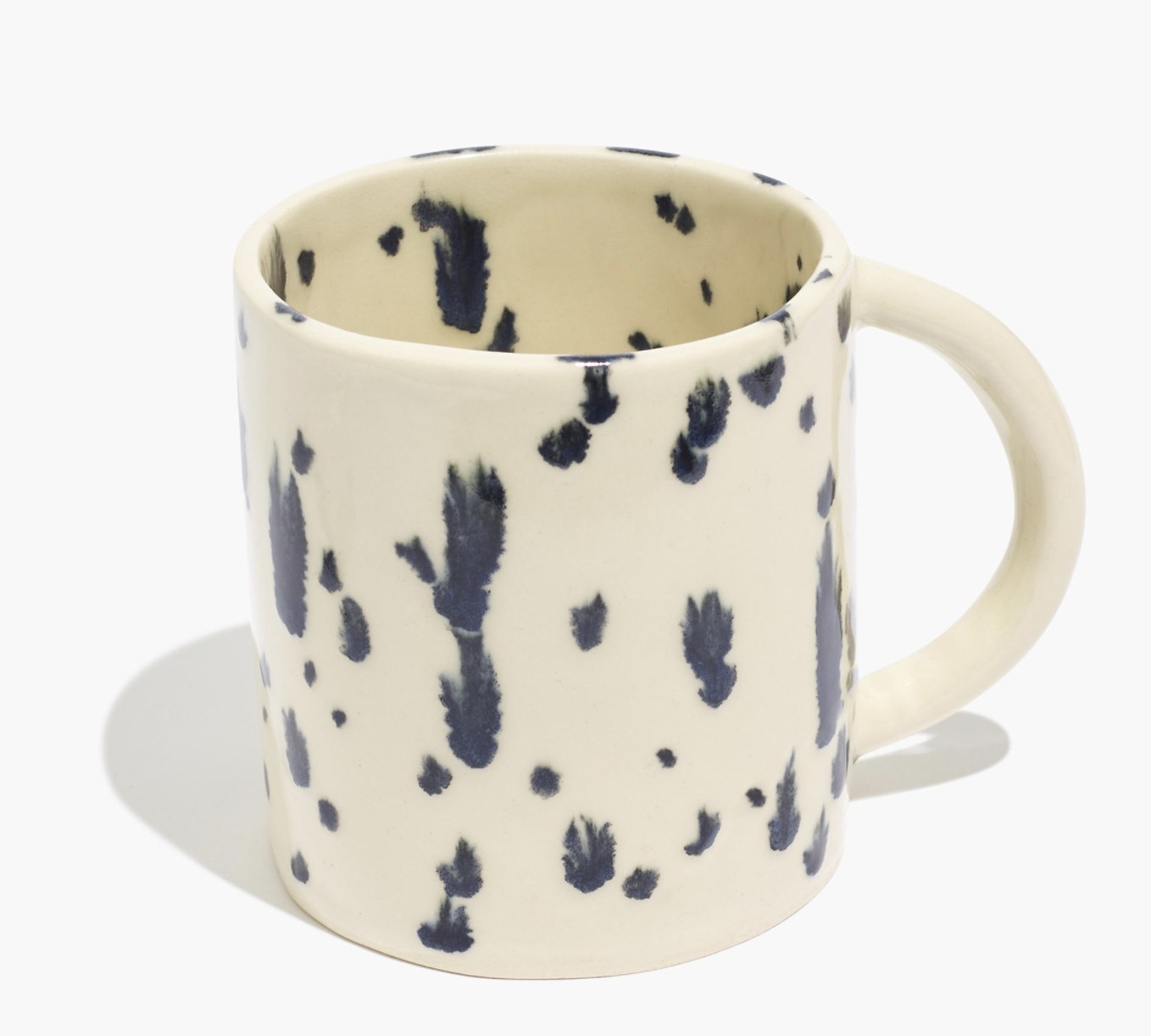 a cream-colored mug with black specks in a cow pattern