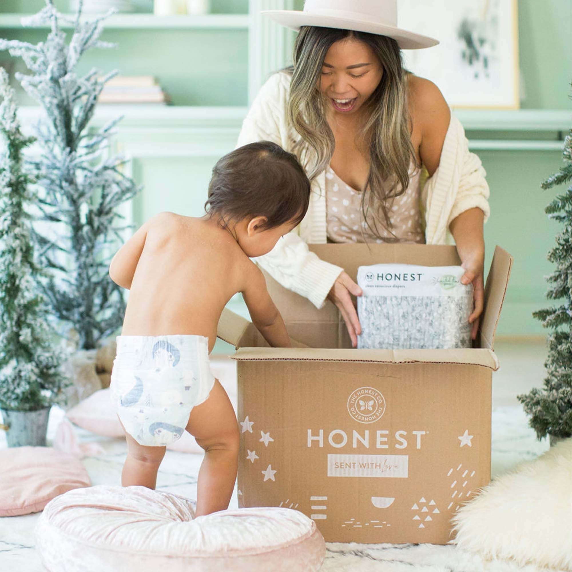 A parent and baby wearing a diaper pulling diapers out of a box