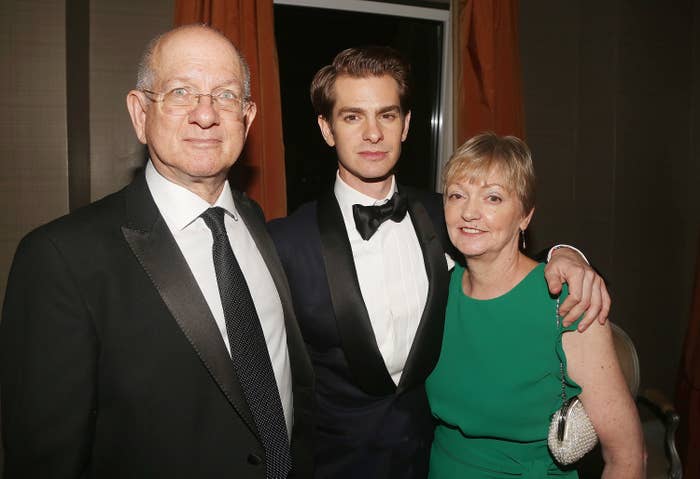 Andrew Garfield stands with his parents with an arm around his mother