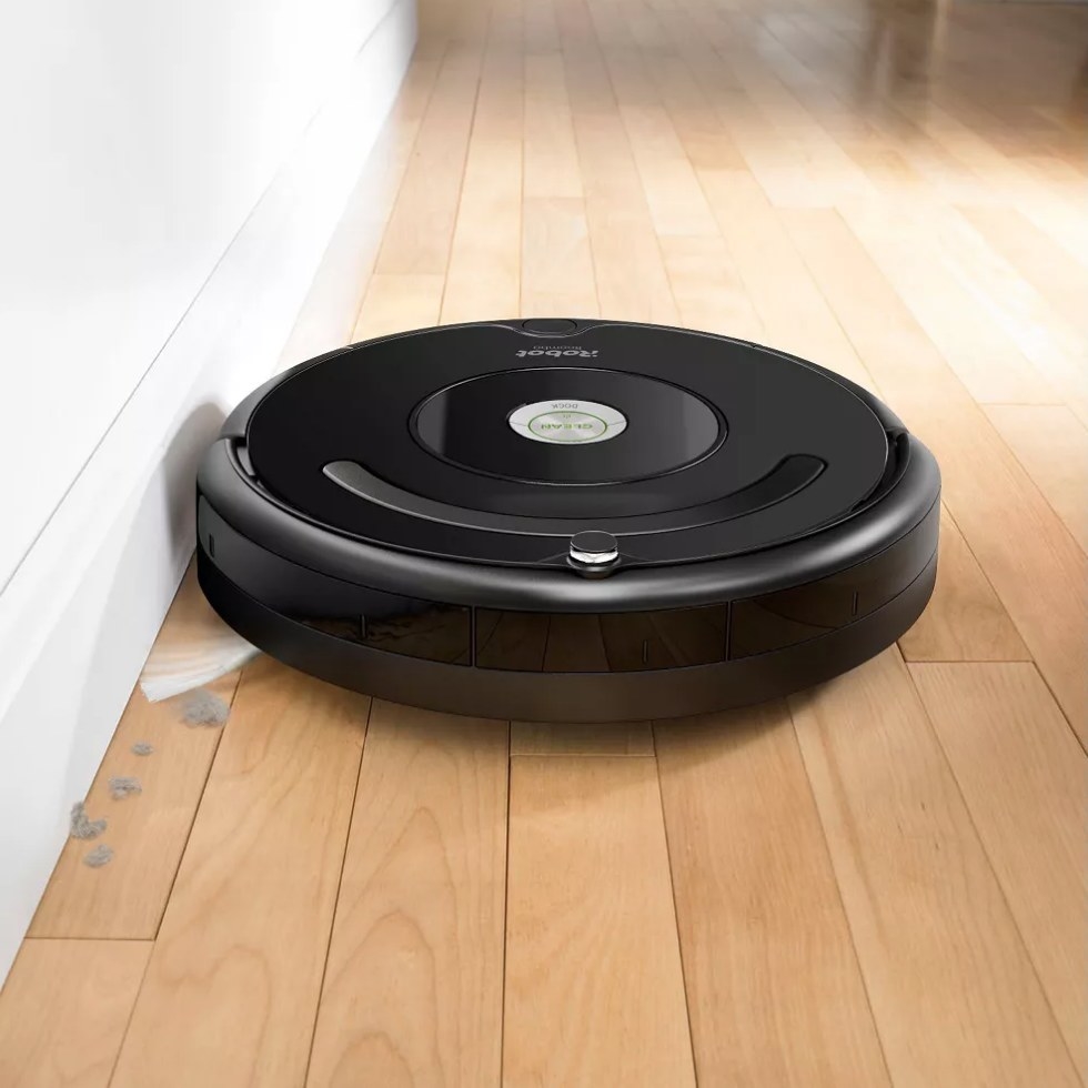 Black, round Roomba vacuum on hardwood floor