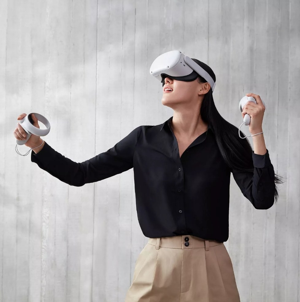 Model wearing white virtual reality goggles holding white controls