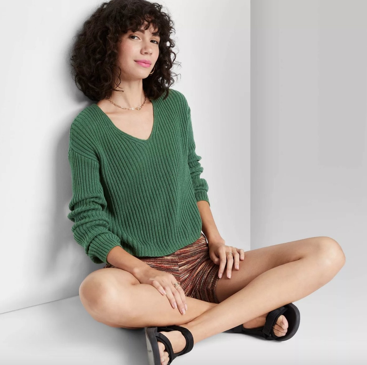 Model wearing green knit sweater with brown shorts