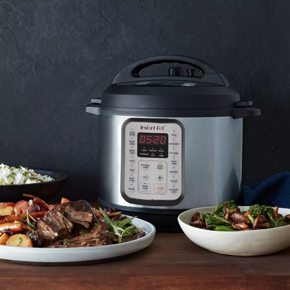 Instant Pot behind plates of beef stew on wooden table