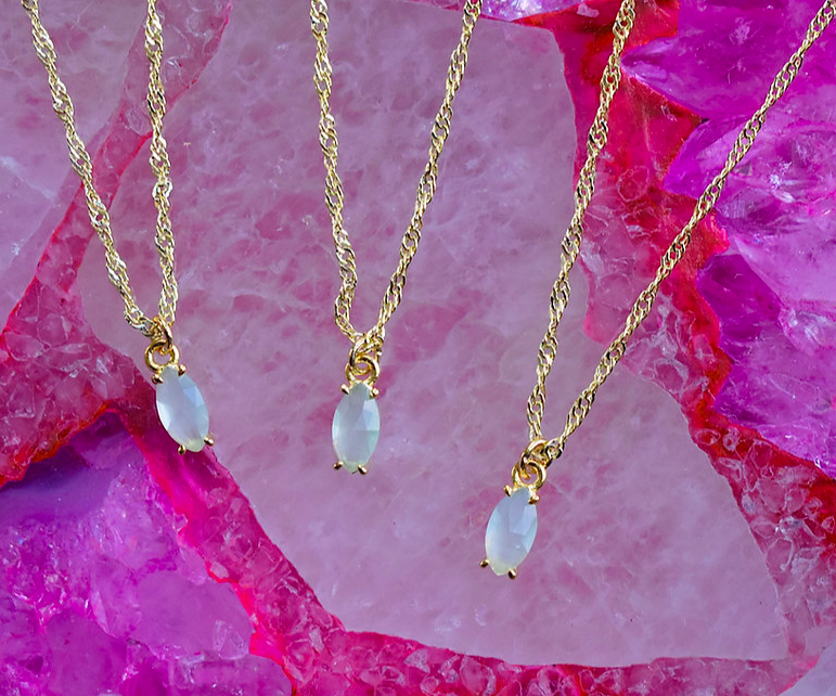 three gold chain necklaces with an oval white stone as the charm