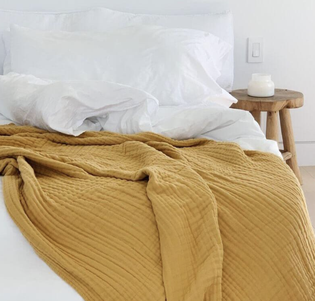 soft knit yellow blanket on bed with white bedding