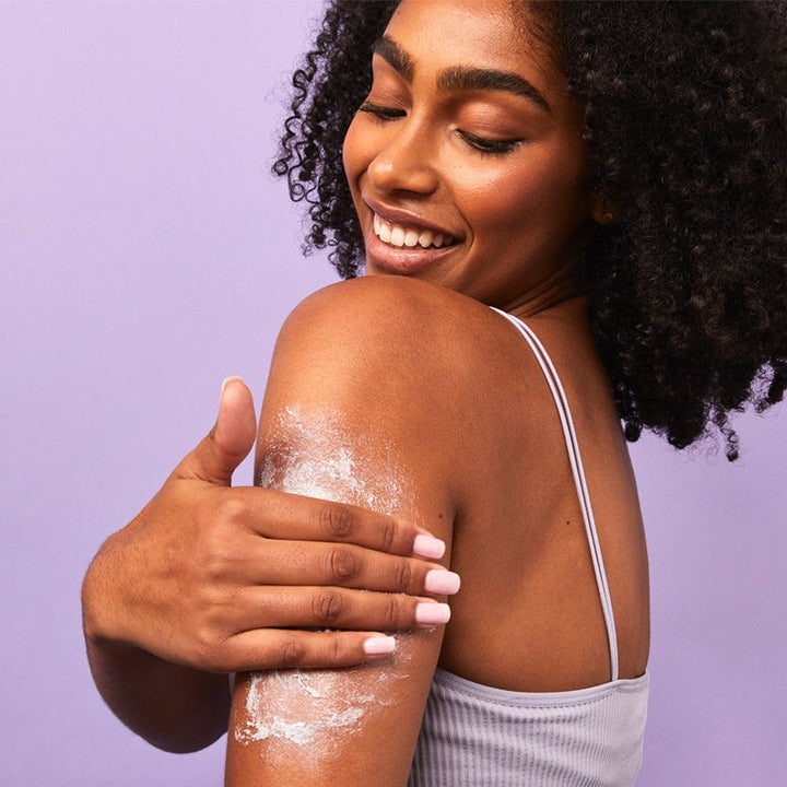model rubbing white cream onto the back of their arms