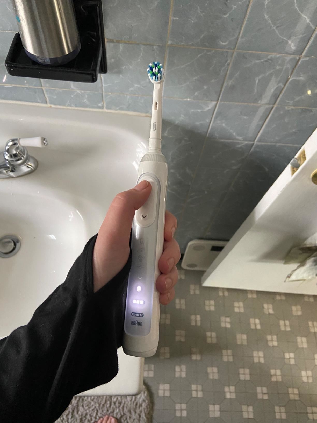 reviewer holding the white toothbrush