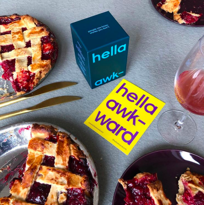 a conversatino card sitting on a dinner table beside a yummy-looking cherry pie and a glass of wine