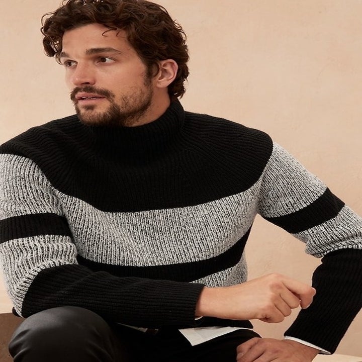 Model wearing a black knit sweater with thick grey stripes