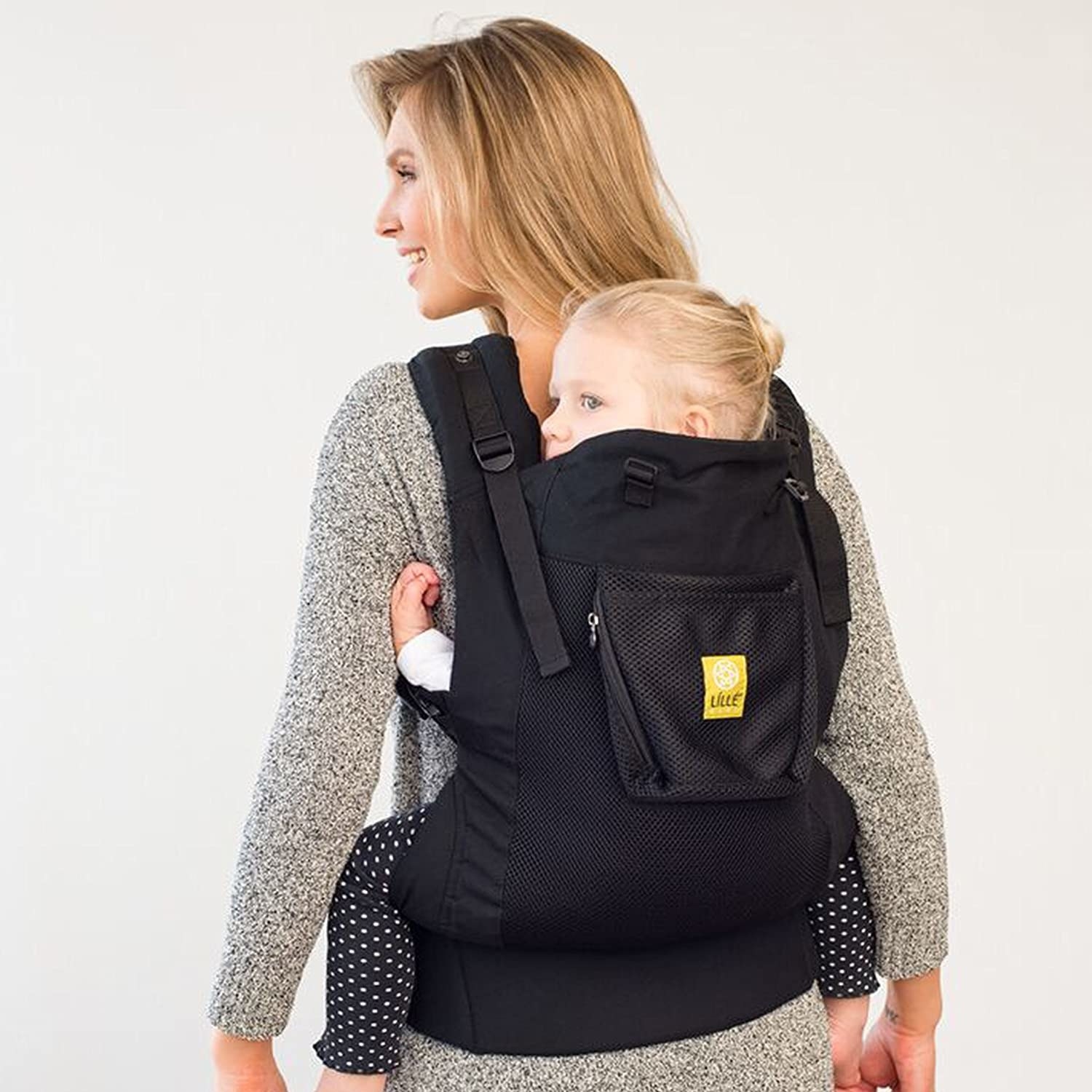 Model with a black carrier with a toddler strapped to their back