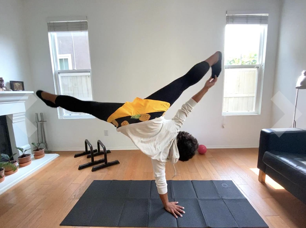 Reviewer doing yoga on a black mat in their home