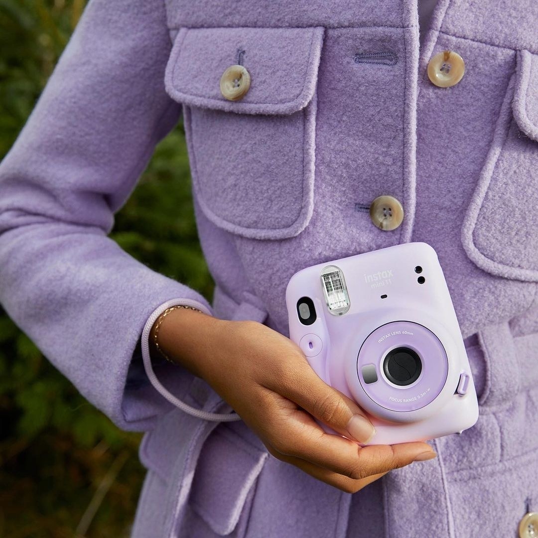 a person holding up the fujifilm instax camera
