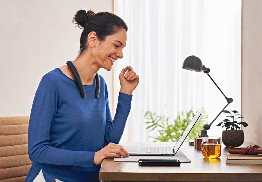 someone working on a laptop while wearing the neckband