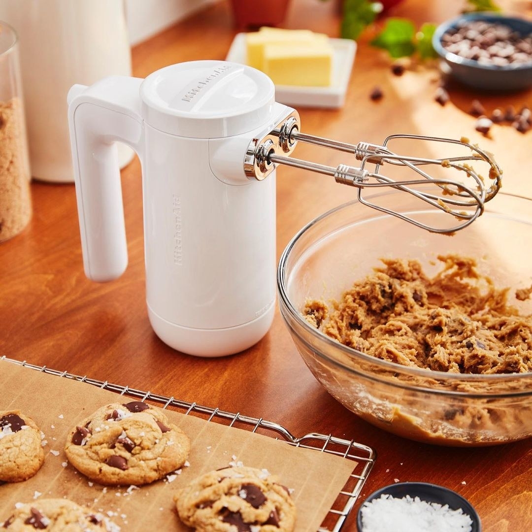 the handheld mixer dripping with cookie batter on a kitchen counter