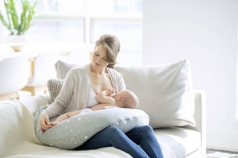 A mother breastfeeding her child on a maternity pillow.