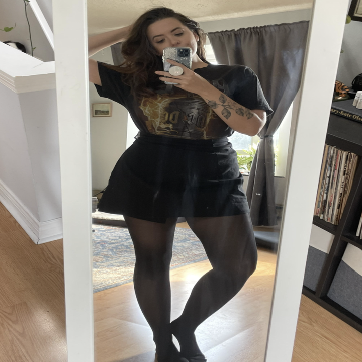 Alice wearing the tights with a skirt and tee and taking a selfie in a mirror
