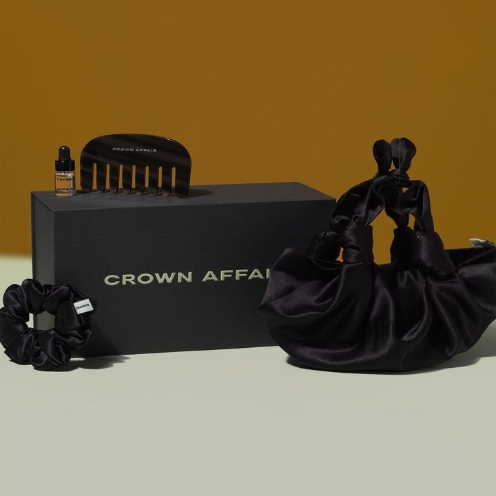 gift set featuring a hair oil, a hair comb, a scrunchie, and a bag