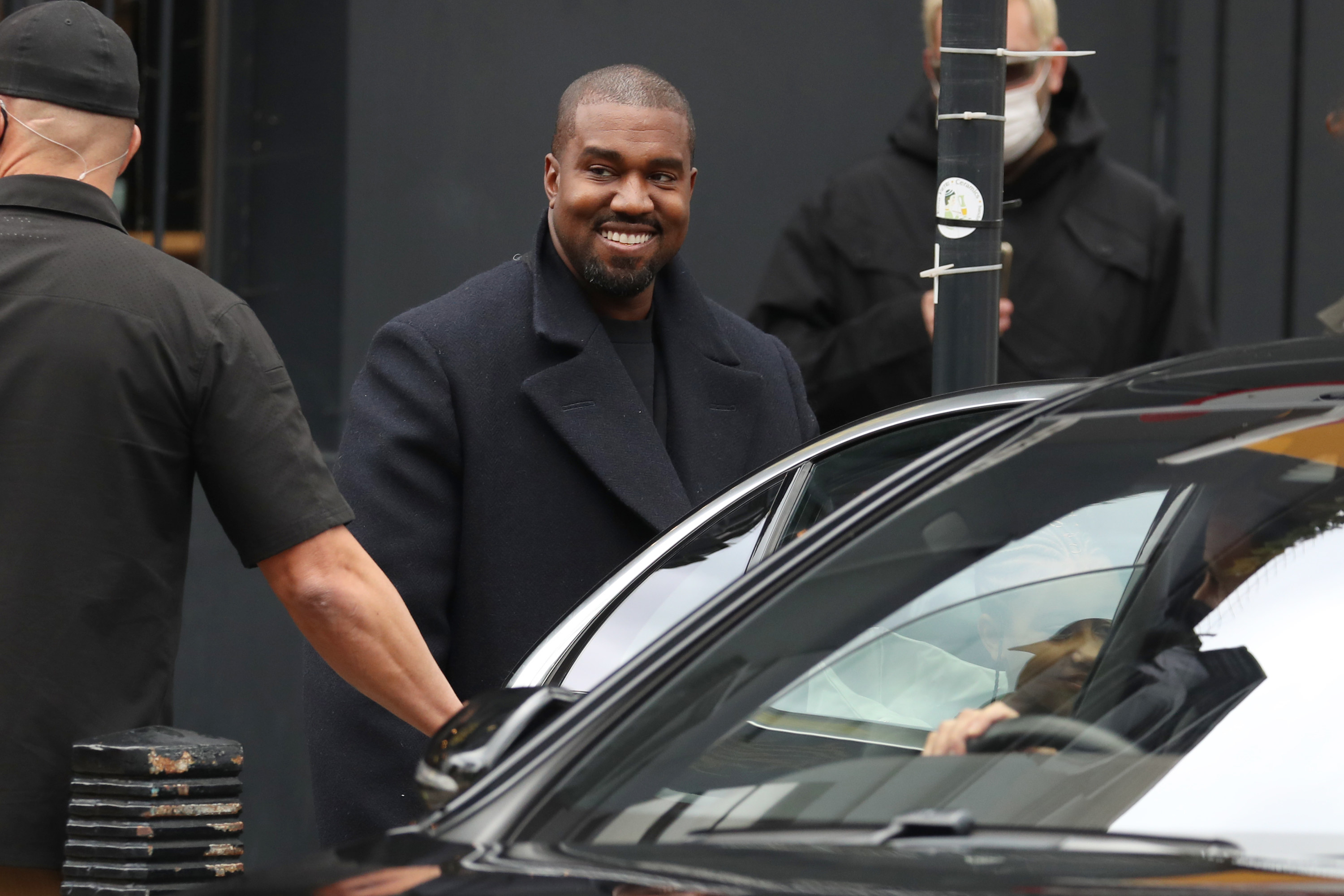 Kanye smiling by a car