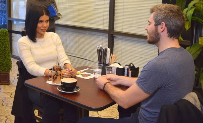 two people from reality tv sitting in a small cafe
