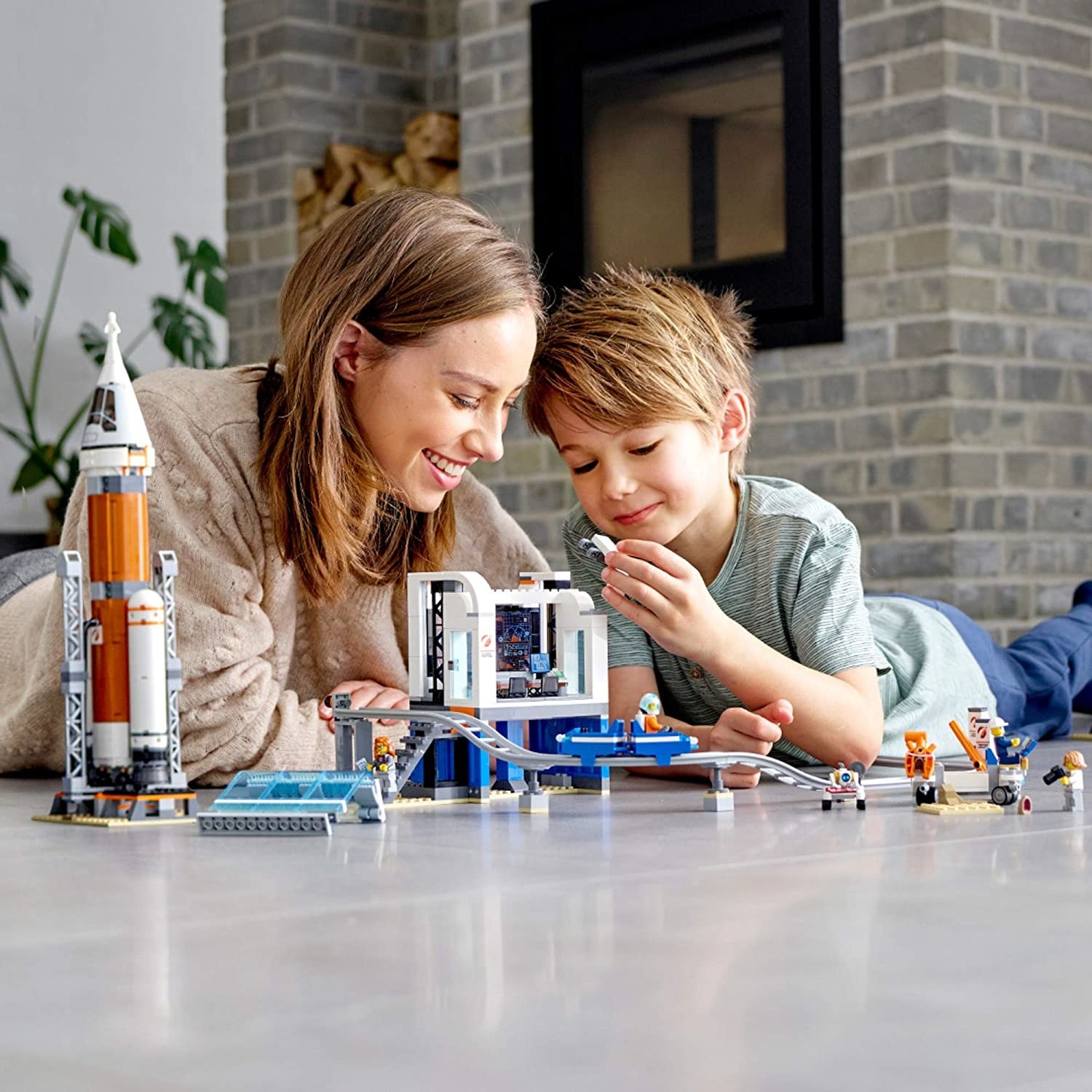 A parent and child playing with the set on a tile floor
