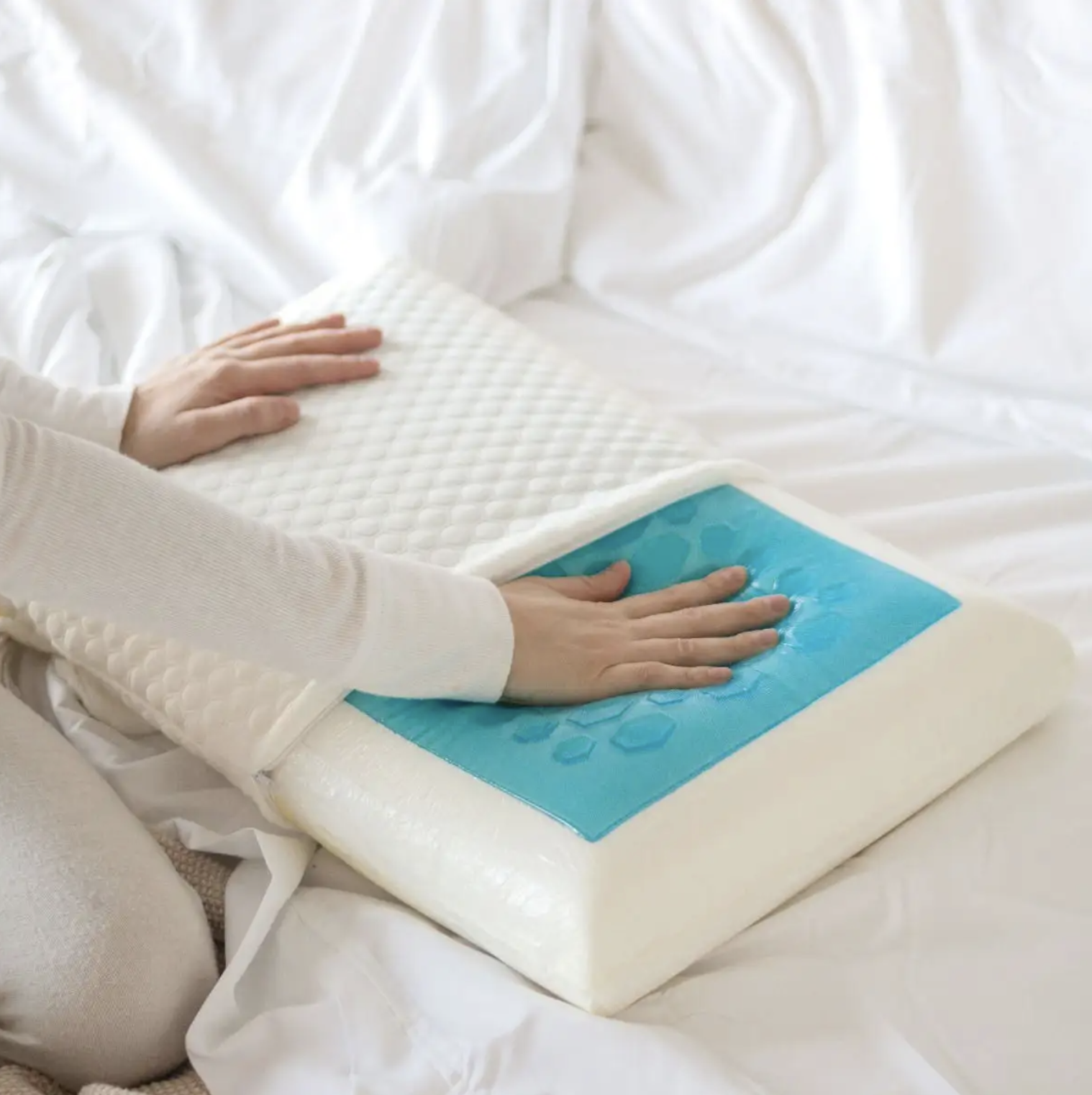 A person sitting on a best pressing down on the centre of the pillow