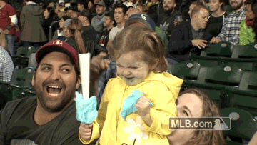 A girl has wide eyes after eating cotton candy at a baseball game