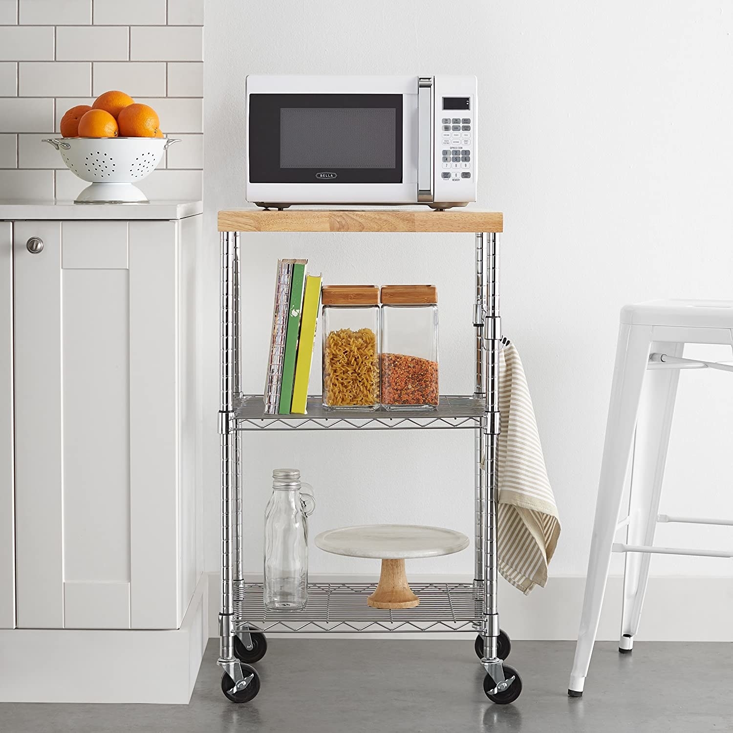 The rolling cart in a kitchen with pasta, cookbooks, and display items on it
