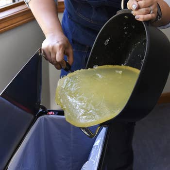 model scooping a large block of solidified grease into the trash